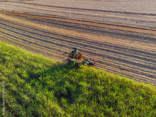 Farm Tractors working on sugar cane harvest plantation aerial view