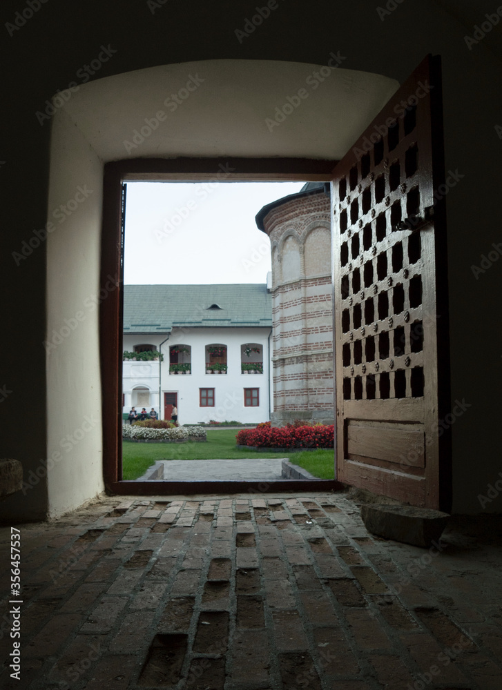 Fototapeta premium Tranquil atmosphere at Cozia Monastery, the 14th century architecture, through the huge wooden door.
