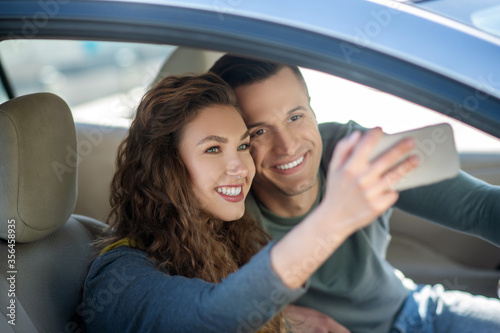 Young couple sitting in the car, making selfie and smiling © zinkevych