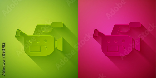 Paper cut Cinema camera icon isolated on green and pink background. Video camera. Movie sign. Film projector. Paper art style. Vector Illustration.