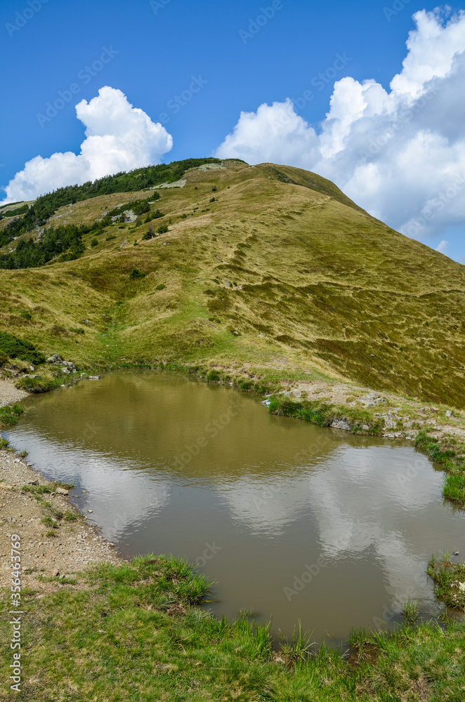 Mountain Lake in the high Carpathian mountains of Ukraine with clouds and green pasture in summer