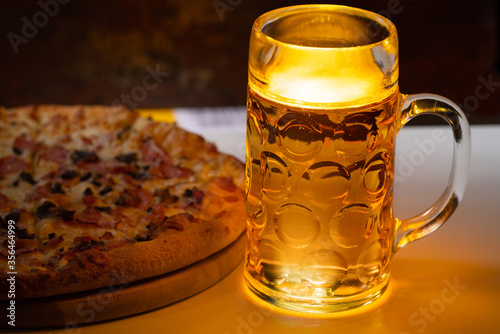 Cold beer in a glass tankard with Italian pizza