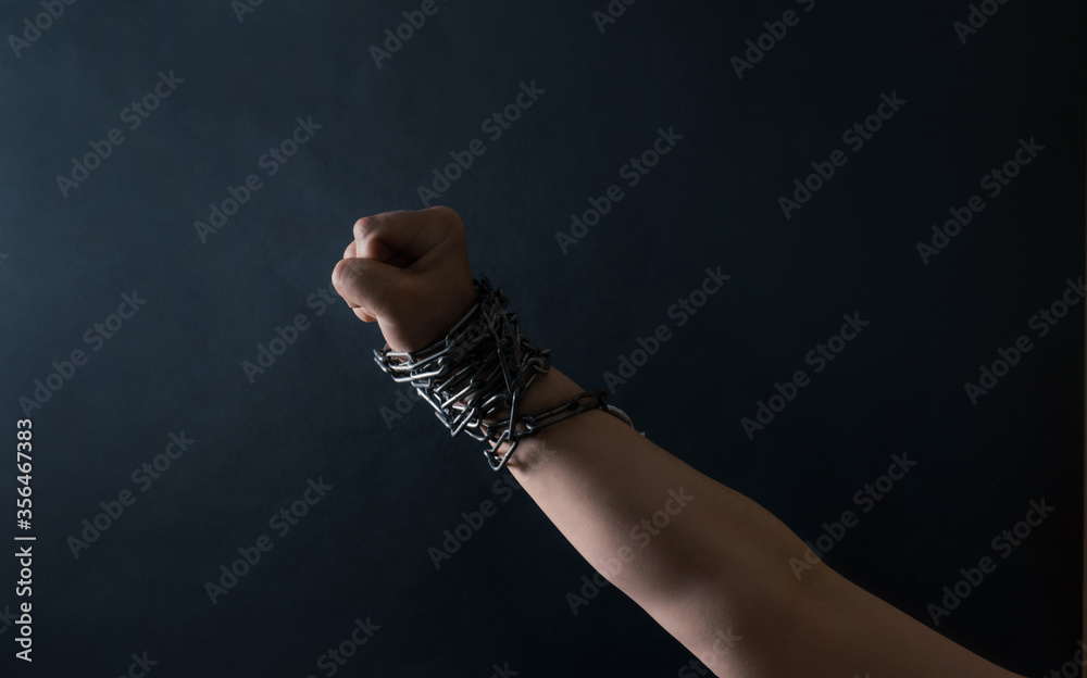 Fist of Hand are chained in chains on the black background, concept of