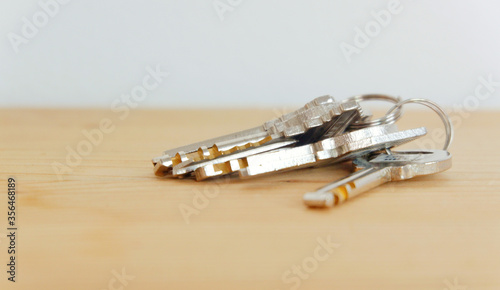 Bunch of keys on a shaped keychain at wooden table background. Concept for real estate or renting home with copy space,Close up. 