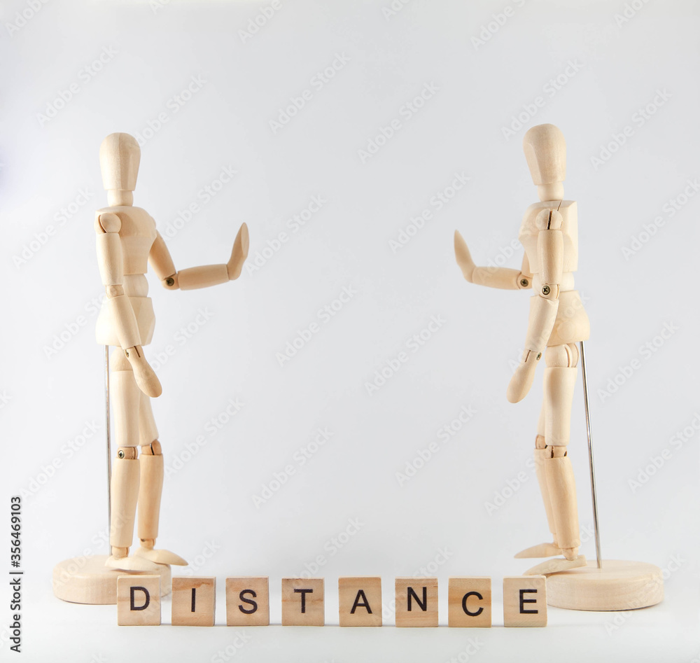 Two wooden figures keep distance on white background. Wooden puppets doing stop gesture with word distance. Social distancing concept during coronavirus pandemic crisis. COVID19 Two wooden figures keep distance on white background. Wooden puppets doing stop gesture with word distance. Social distancing concept during coronavirus pandemic crisis. COVID19