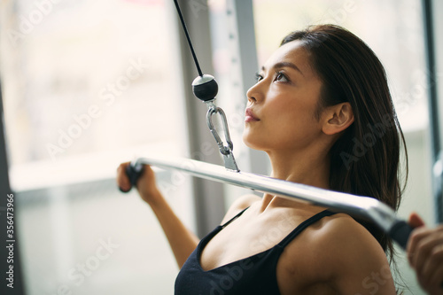 ラットプルマシンでトレーニングをする日本人女性