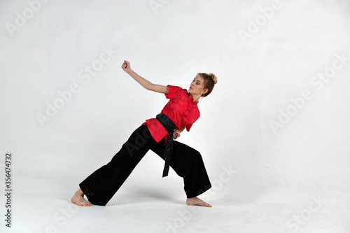 beautiful girl in black and red does exercises for mastery of martial arts
