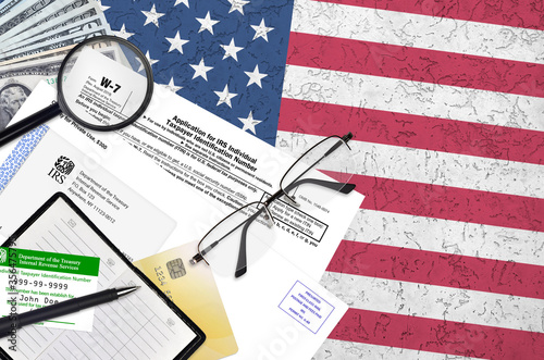 IRS form W-7 Application for IRS individual taxpayer identification number lies on flat lay office table and ready to fill. U.S. Internal revenue services paperwork concept photo