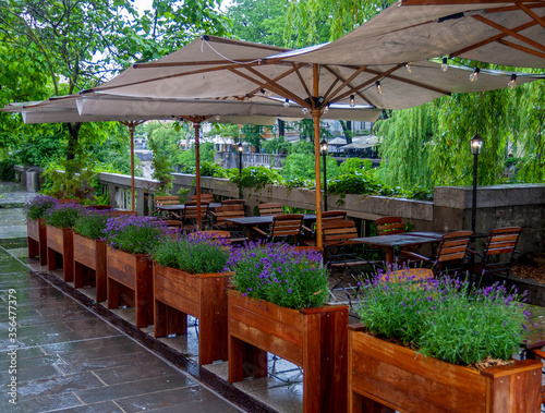 summer terrace of a small cozy restaurant near the river during rains © Eugene