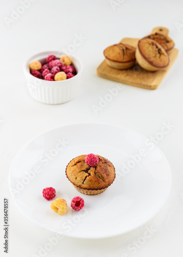 Cupcake with raspberries made from coconut and almond flour on a white plate. Healthy food, vegetarian. No sugar, gluten, lactose.