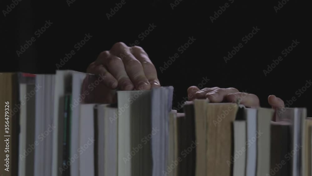 Manos agarrando libros en biblioteca con fondo negro