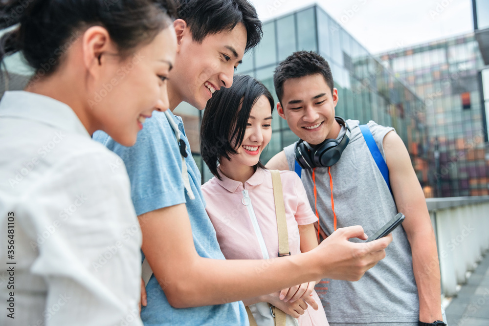 Outdoor four college students watch mobile phone Outdoor four college students watch mobile phone