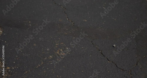 A closeup view of a used surgical mask being picked up in a store's parking lot. Shot at 48fps slow motion.  	 photo