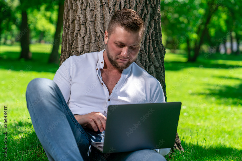 a man of European appearance works remotely using a laptop while he is in the park a man of European appearance works remotely using a laptop while he is in the park