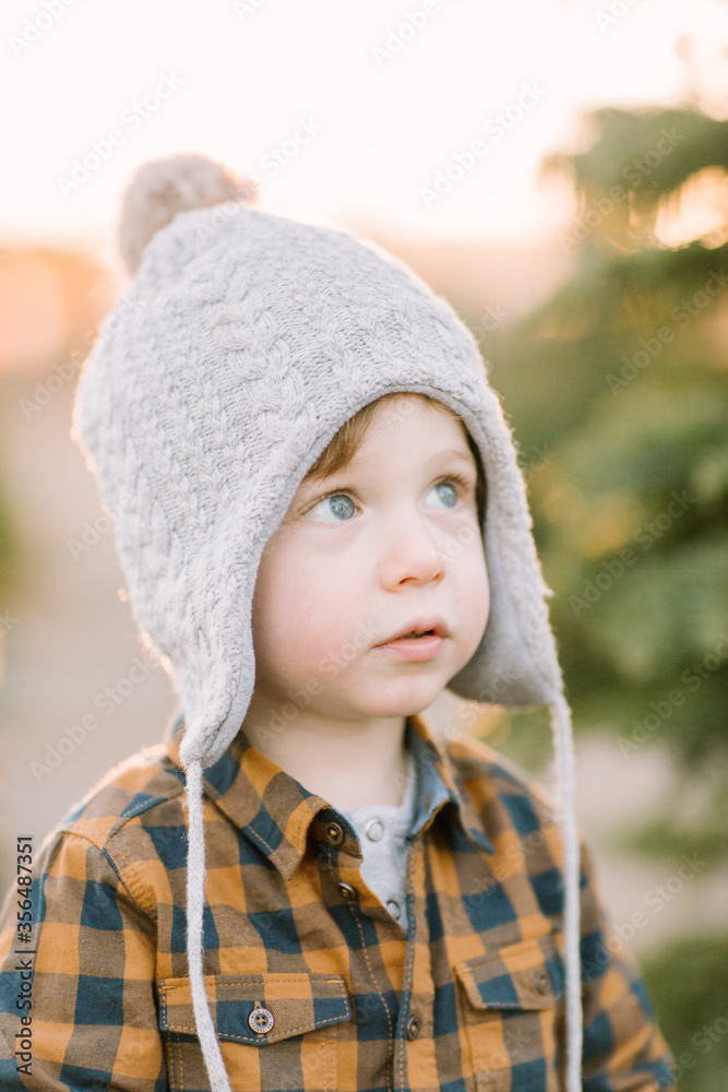 Toddler wearing winter hat looks up magical, holiday, thoughtful Toddler wearing winter hat looks up magical, holiday, thoughtful