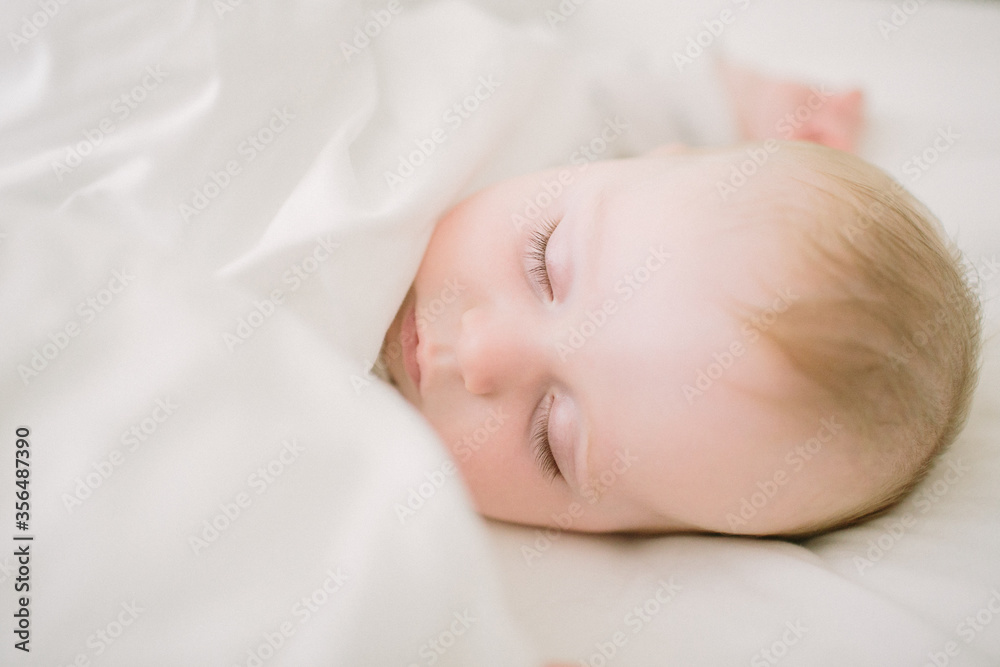 Peaceful and ethereal sleeping baby surrounded in white blanket Peaceful and ethereal sleeping baby surrounded in white blanket