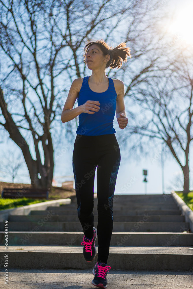 Portrait of a woman running on staircase outdoors in a park Portrait of a woman running on staircase outdoors in a park