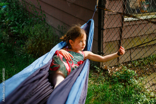 A small girl in a bright colored tutu plays in a hammock in sunshine photo