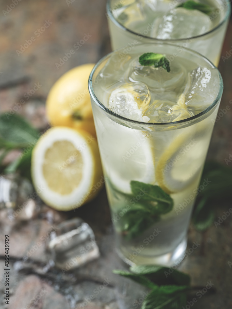 Fresh lemonade cocktail with ice, mint and lemon by barista cooked on table bar background with ingredients. Fresh lemonade cocktail with ice, mint and lemon by barista cooked on table bar background with ingredients.