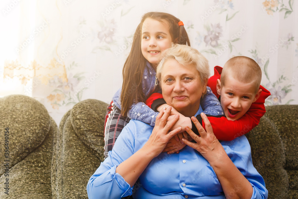 Grandmother and grandchildren sitting together on sofa in living room Grandmother and grandchildren sitting together on sofa in living room