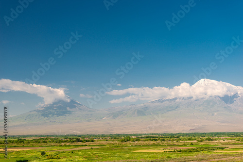 Green field and high mountain Ararat against the blue sky on a sunny day, Armenia