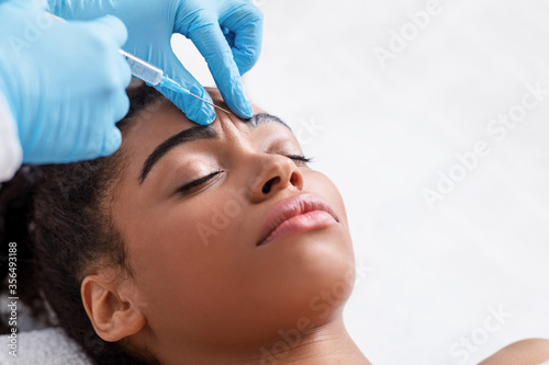Obraz na plátně Young black woman receiving botox injection at beauty salon