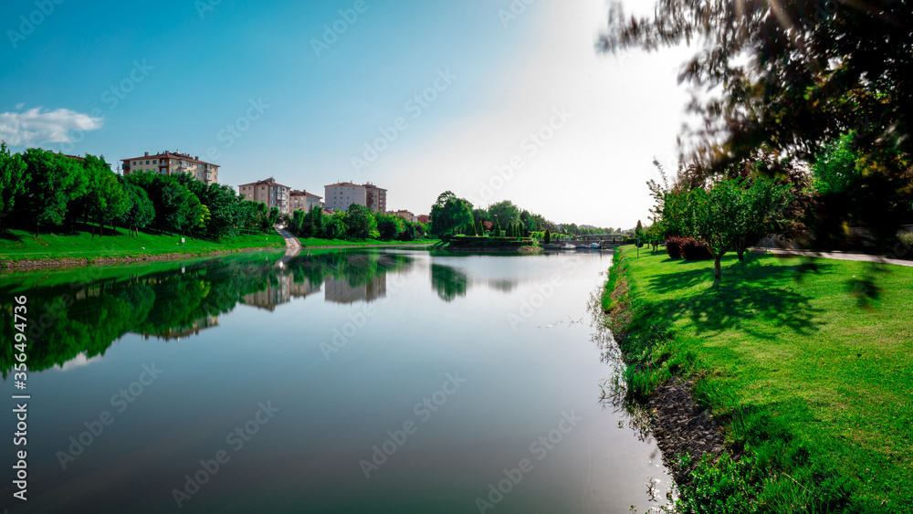Scenic view natural park. Eskisehir, Turkey. The river flowing through the city. Reflections on the water. Colorful landscape. Sunny and windy day. Long exposure.