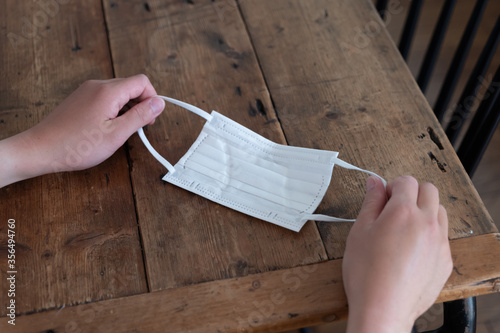 木目のテーブルの上でマスクを手にとっている