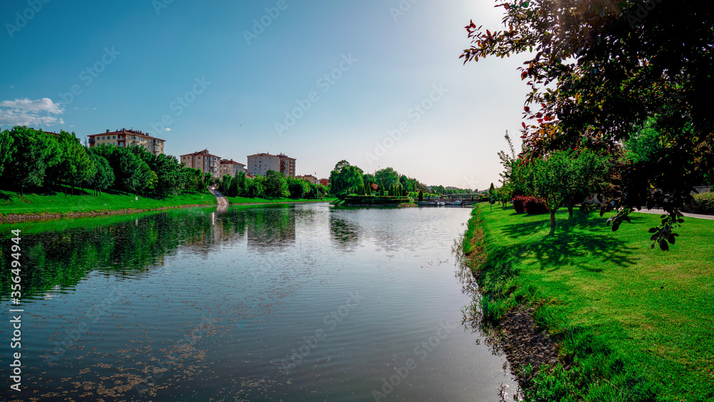Scenic view natural park. Eskisehir, Turkey. The river flowing through the city. Reflections on the water. Colorful landscape. Sunny and windy day.