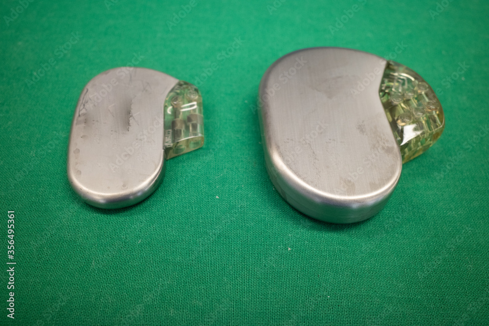 pacemaker lies directly next to a defibrillator on a green surgical ...