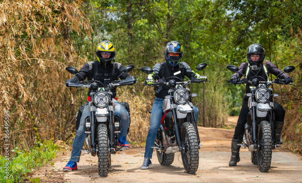 three friends riding their scrambler motorcycles through forrest three friends riding their scrambler motorcycles through forrest