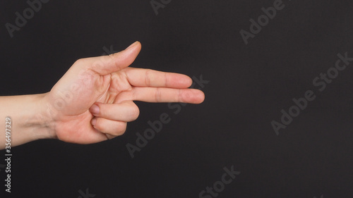 male model is doing point two finger or gun Hand Sign on black background.