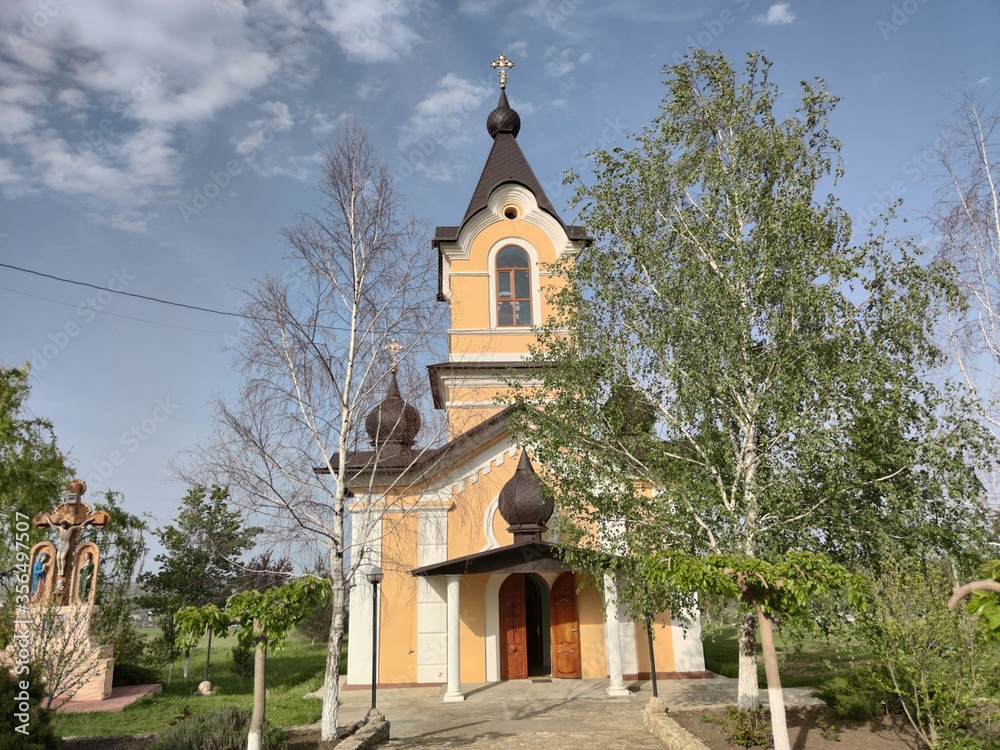 Old orthodox church of yellow color. White birch trees. Blue sky with olaks. Tsypovo. Moldova