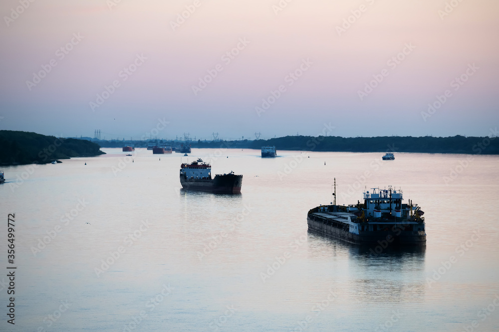 barges and fishing and merchant ships on the river at dusk against the background of wires and poles. industrial area of the city. port