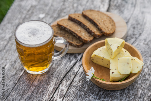 Glass of light beer with cheese and rye bread