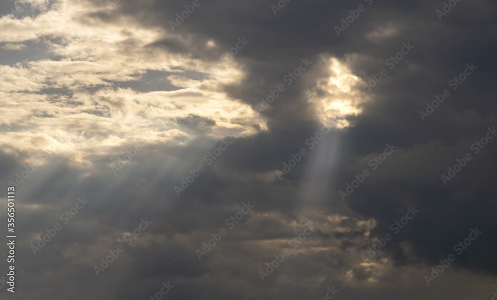 gray Cumulus clouds in a blue sky with rays of the sun