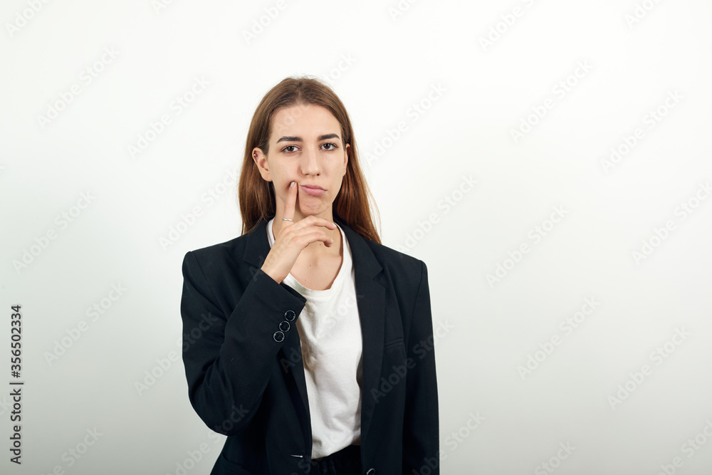 Hand on chin thinking about question, pensive expression. Doubt. Thoughtful face. Using that incredibly sharp business mind. Young attractive woman with brown hair in a light t-shirt and black jacket Hand on chin thinking about question, pensive expression. Doubt. Thoughtful face. Using that incredibly sharp business mind. Young attractive woman with brown hair in a light t-shirt and black jacket