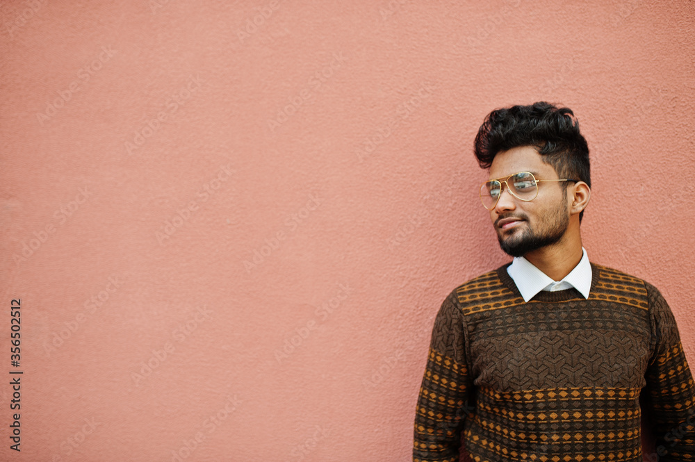 Fototapeta premium Portret model młody stylowy indyjski mężczyzna w okularach na białym tle na tle różowej ściany.