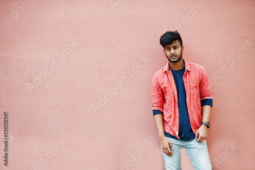 Portrait of young stylish indian man model isolated on pink wall background.