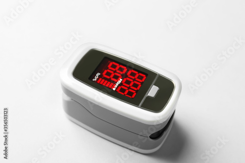 Modern fingertip pulse oximeter on white background, closeup