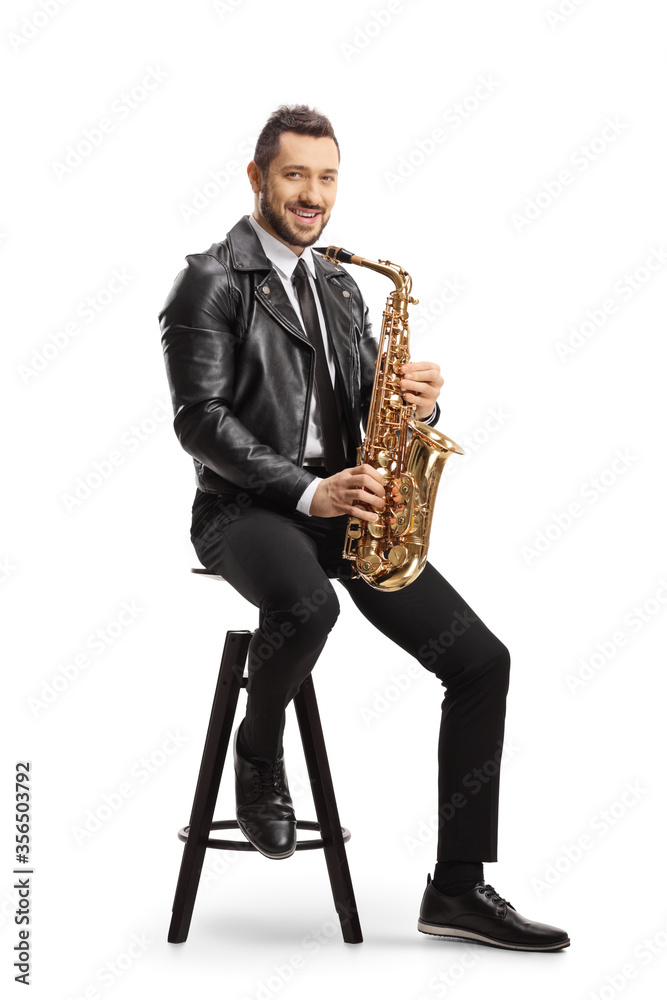Naklejka premium Man in a leather jacket sitting on a chair and holding a saxophone