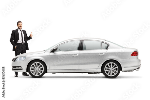 Businessman standing next to a silver car and showing thumbs up