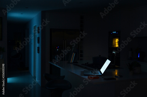 Shot of a laptop illuminated in a kitchen at night