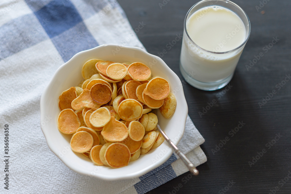 Tiny pancake cereal and milk on dark rustic background Tiny pancake cereal and milk on dark rustic background