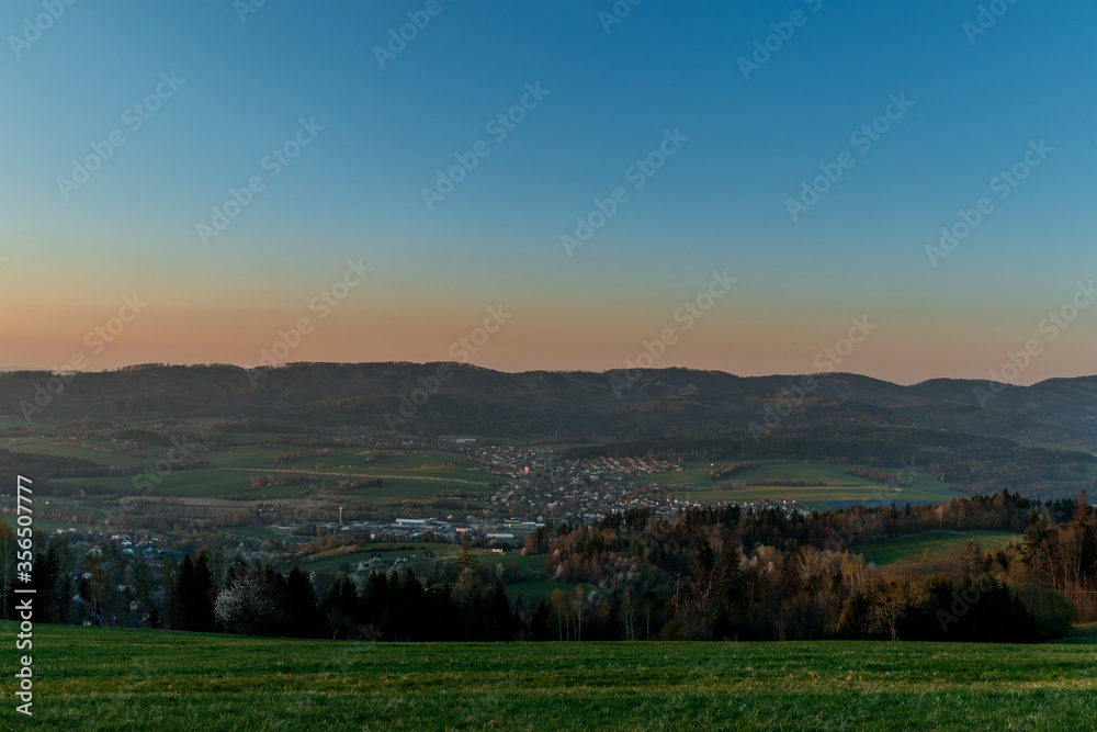 Sunset on a mountainous landscape with a village lying under the mountains Zasova Czech Republic.