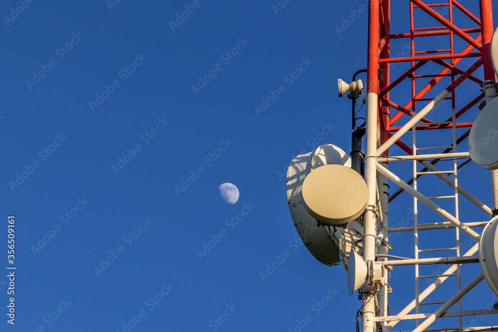 Closeup of a broadcast tower full of devices with a blue sky in the background.