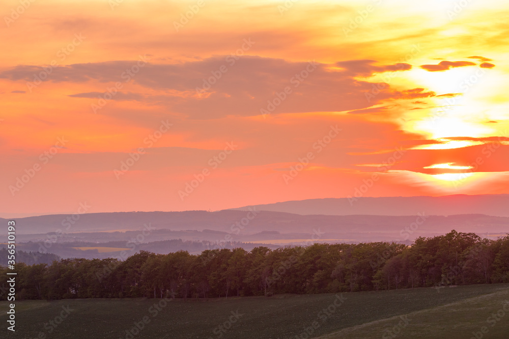 The setting sun over the forested mountain landscape of the Beskydy region, the sun sets beyond the horizon. The setting sun over the forested mountain landscape of the Beskydy region, the sun sets beyond the horizon.