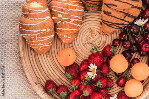 tray with croissants, strawberries, cherries and apricots