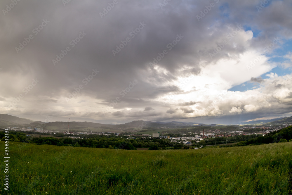 Landscape view of the town of Valasske Mezirici during the rain in the hills on the horizon where the sun shines into the landscape.