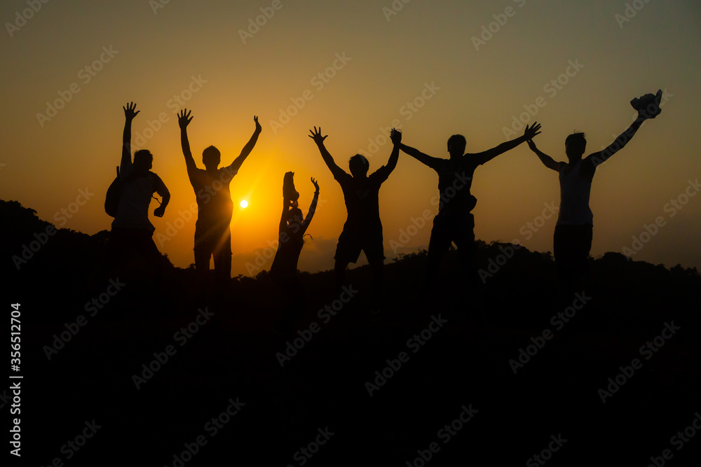 Group of friends jumping in joy over success - silhouette sunset
